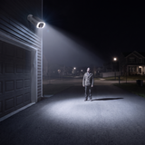 A man stopped in the camera's floodlight at night, looking up at it