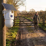 The camera's lower ball turned to follow a man walking up a farm lane