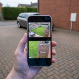 A phone held up outdoors showing the camera's wide and close views at the same time