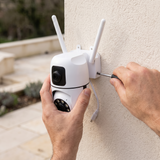 Hands fitting the camera's bracket to a rendered wall with a screwdriver