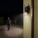 A man on a gravel drive at night lit in full colour by the camera's own light